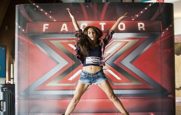 Clara Neto a saltar de braços e pernas abertos em frente ao logótipo do Factor X