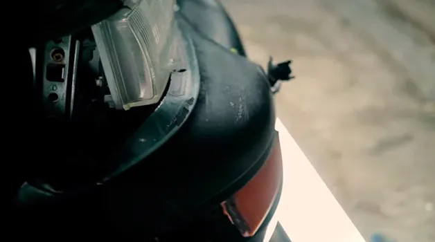 Pormenor de um farol solto e de plásticos partidos na frente do Nissan Maxima