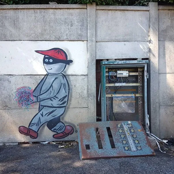Boneco pintado num muro a fugir com cabos coloridos de uma caixa elétrica aberta