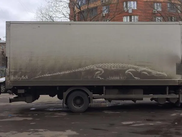 Desenho de um crocodilo feito no pó da caixa de um camião sujo
