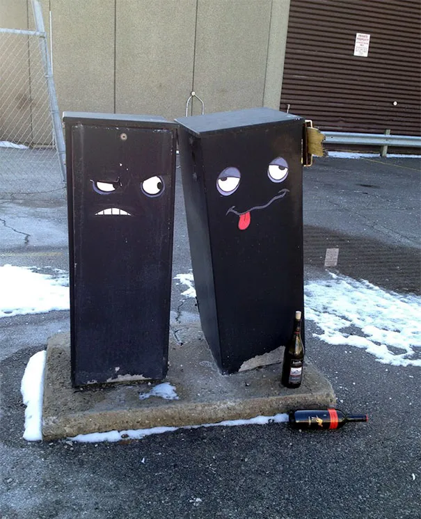 Duas caixas elétricas pretas com caras pintadas, uma delas com ar de bêbeda e garrafas no chão