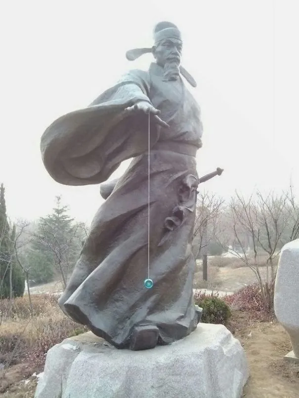 Estátua de um homem com roupas largas ao vento, a segurar um ioiô azul