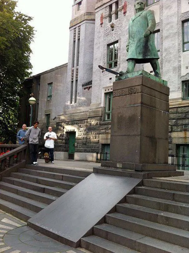 Estátua em cima de um pedestal com uma rampa de skate colocada sobre as escadas à frente