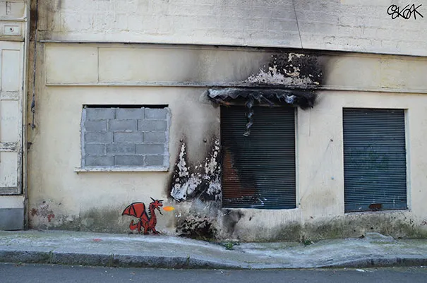 Fachada queimada por um incêndio com um pequeno dragão vermelho pintado junto às marcas do fogo