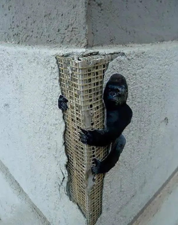 Pequena figura de King Kong agarrada a uma esquina de betão partida, como se fosse um arranha-céus