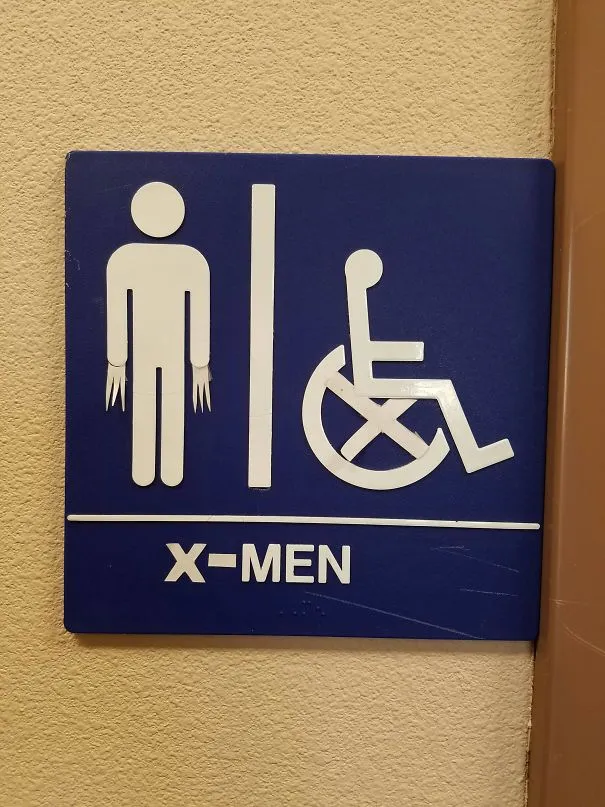 Placa de casa de banho com um homem e uma cadeira de rodas, alterada para ficar com garras e a palavra X-Men