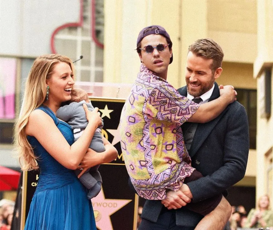 Average Rob ao colo de um ator de fato numa cerimónia do Passeio da Fama de Hollywood, ao lado de uma mulher com um bebé