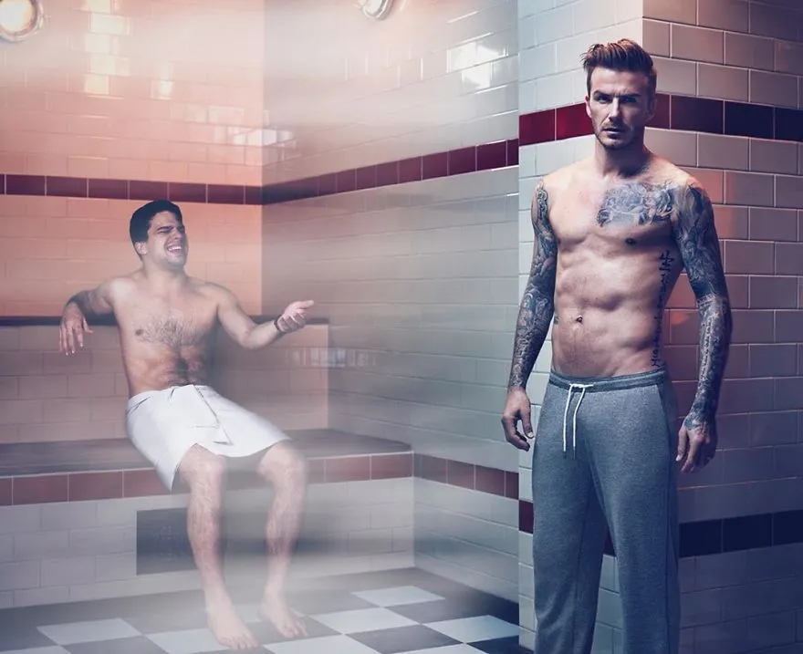 Average Rob de toalha num banho turco ao lado de um homem tatuado de fato de treino
