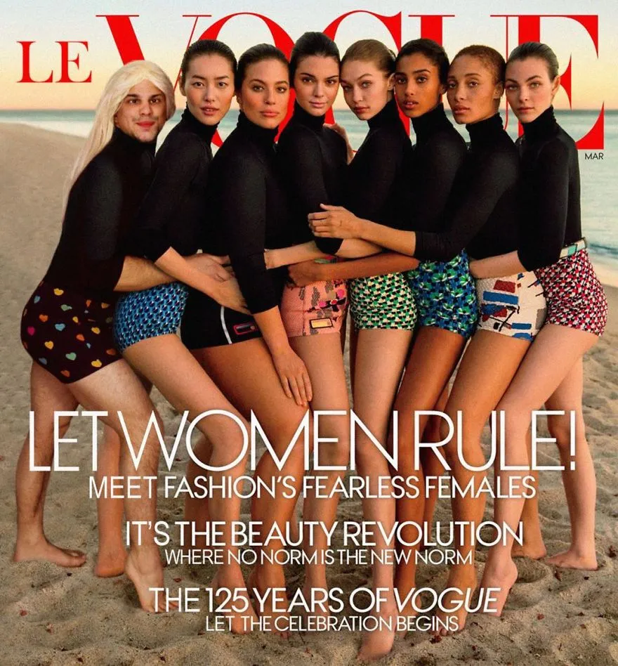Capa da Vogue com várias modelos de camisola preta e cuecas coloridas numa praia, com Average Rob de peruca loira no grupo